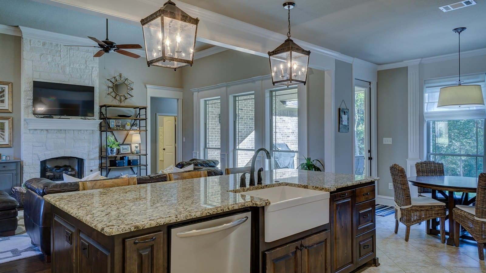 A modern open-plan kitchen with a stainless steel dishwasher built into the island beside the sink